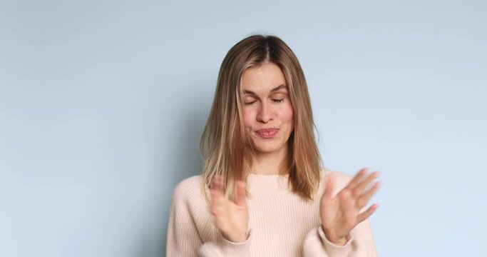 Pretentious blonde straight hair woman in sweater clapping, and looking annoyed over blue background. Girl applauds with a grin, sarcasm sarcastically clapping her hands.