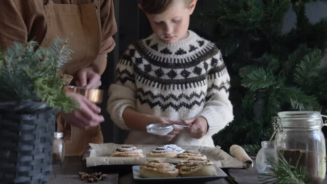 Mother and son eating baked Swedish Cinnamon Buns on table at home