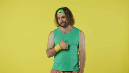 Man in green top and headband looking at the camera, winking and showing thumbs up sign. Isolated...