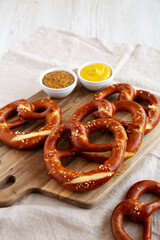 Homemade Soft Bavarian Pretzels with Mustard on a wooden board, side view. Copy space.