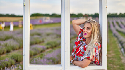 Young beautiful woman sits on a vintage swing in a lavender field.