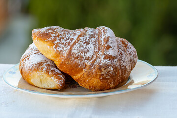 Italian sweet breakfast, fresh baked croissant buttery pastry with sugar powder