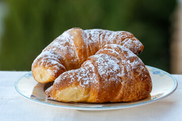 Italian sweet breakfast, fresh baked croissant buttery pastry with sugar powder