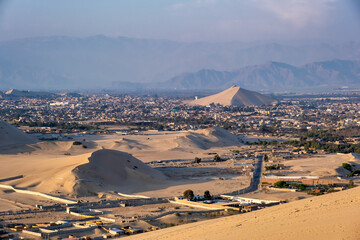 City in Peru surrounded by sand dunes at sunset.