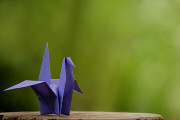 Purple origami paper crane on natural background.