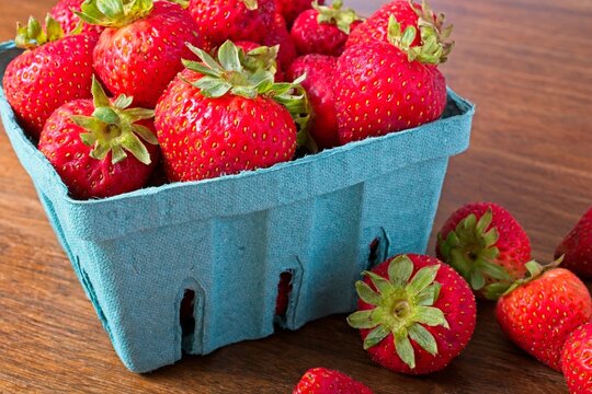 Close up quart of strawberries on a rustic wooden table.