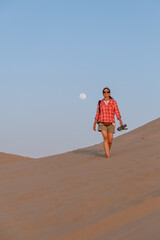 Girl walking on the sand with the full moon behind her