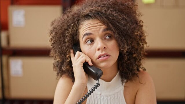 Young beautiful hispanic woman ecommerce business worker talking on telephone tired working at office