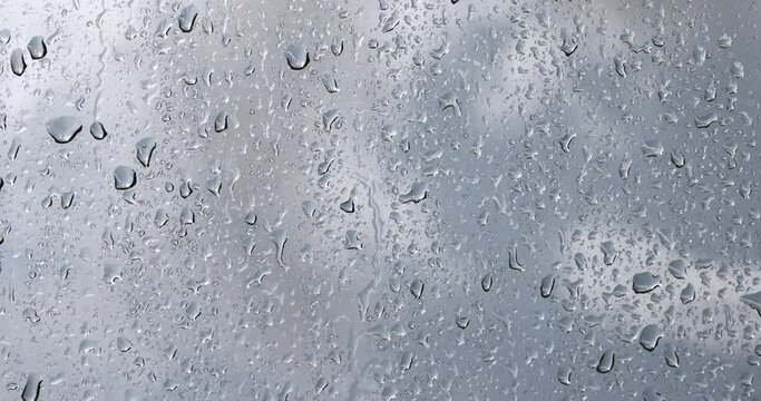 glass with water drops during rain, glass covered with rain water drops in a building window