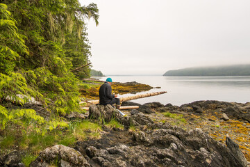 art in nature: an artist sits sketching on a wild rocky intertidal seashore shot in hieltsuk territory central coast british columbia room for text
