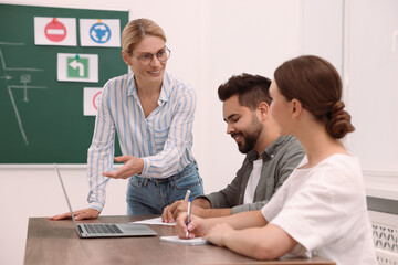 Happy teacher giving lesson in driving school