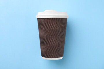 One paper cup on light blue background, top view. Coffee to go