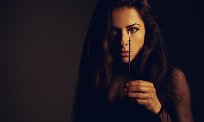 Beautiful makeup female model holding in hand the candle at shado dark night in black dress and...