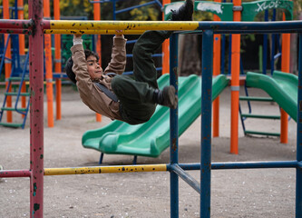 boy playing on playground equipment in a park