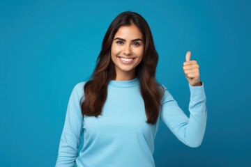 Fototapeta premium Happy businesswoman showing thumb up over blue background. Wearing in blue shirt and Looking at camera.