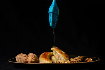 arabic dessert sambuses with walnuts on a black background and syrup with zkittles terpenes, blue brush