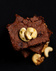 
chocolate mango brownie, with chestnuts on top and a black background, seen from above