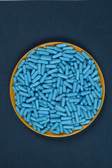 Yellow plate full of blue medicine capsules representing drug overdose