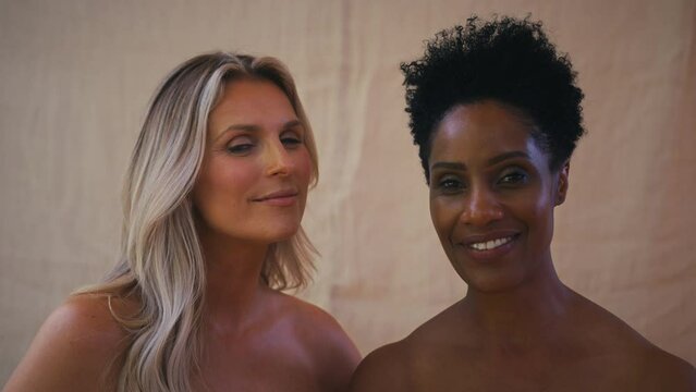 Beauty portrait of two smiling mature women with bare shoulders against natural background - shot in slow motion