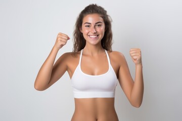 Fototapeta na wymiar Portrait of a smiling sportswoman in white sportswear showing her thumb up and her biceps isolated on a white background and Looking at the camera.