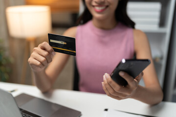 Confident Asian businesswomen sitting at their desks Are using banking applications to buy or pay online mobile bills. and registered her credit card on the website for online purchases.