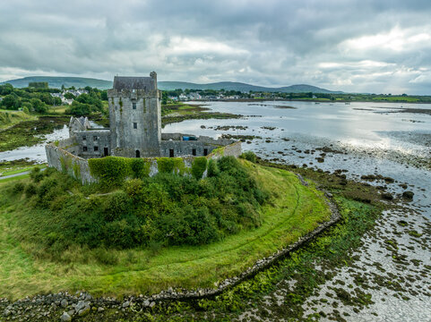 Aerial view of Dunquaire castle in Ireland, typical tower house castle on a small hilltop guarding the road to Galway with colorful sunset sky