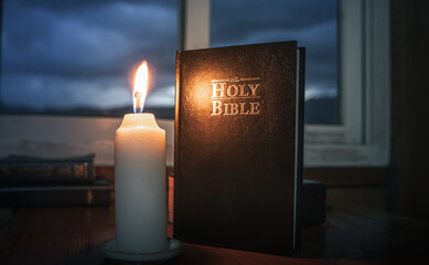 Light candle with holy bible on wooden table at window background, Bible study concept.