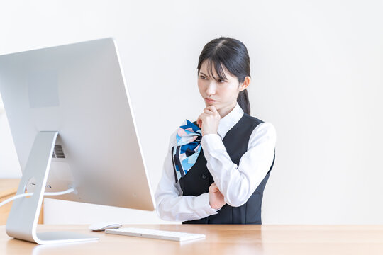 パソコンの前で考える制服を着た日本人女性
