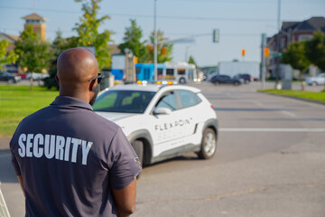 A security guard is controlling the traffic and parking situation at an Asian festival in Canada.