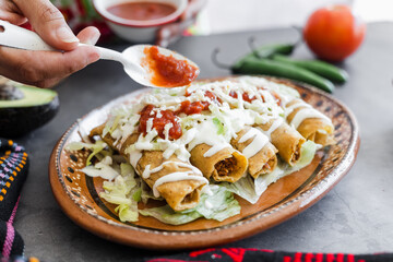 Mexican woman cooking tacos dorados called flautas with chicken, traditional fried food in Mexico Latin America