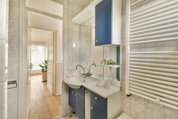 a small bathroom with blue cabinets and white tiles on the walls, along with a wooden door leading...