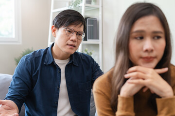 Family problem concept, Asian wife and husband sitting back to back in the living room at home have problems in a relationship and have an argument