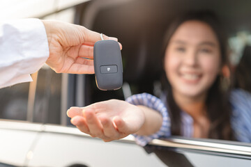 Close up woman hand receiving car remote control from auto dealer rental shop.