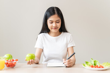Obraz na płótnie Canvas Wellbeing of health with good food control concept. Woman writing the meal note and plan to eat during diet program to loss weight goal for balance nutrition and calories.