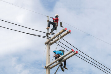 Electricians working on power pole connecting cables