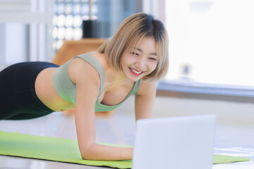 Asian young beautiful female athlete teenager in sportswear sport bra legging stretching body lay down planking on elbows exercising practicing working out abdomen abs on yoga pilates in living room.