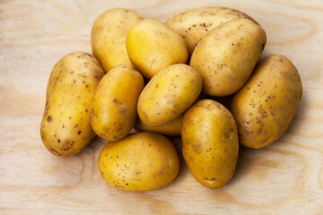 Freshly picked potatoes lie in a pile on a wooden background. Organic healthy food. New crop of young potatoes. Sale of farm natural products