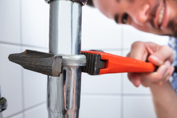 Plumber Repairing Sink In Bathroom