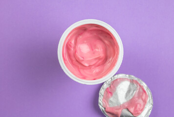 Pink yogurt cup - top view of strawberry yoghurt on lilac background with copy space