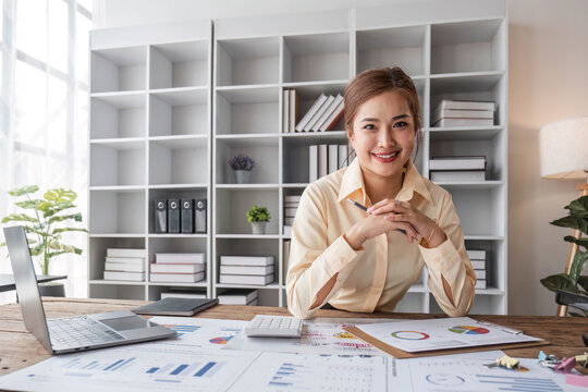 Stressed young Asian businesswoman focuses on rechecking the business financial investment plan's report at her desk.