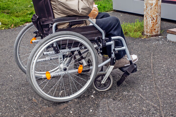 Fototapeta na wymiar A man in a wheelchair sits on the sidewalk on an autumn day
