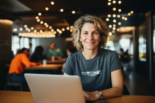 Portrait of smiling mature woman using laptop in cafe during coffee break