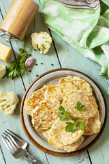 Cauliflower vegetable fritters with cheese on a rustic kitchen table. Fried vegetarian cutlets or...