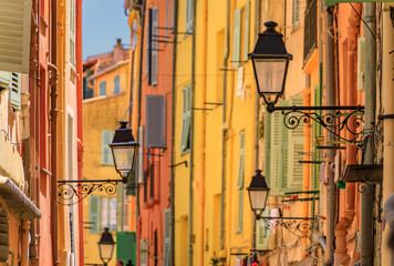 Fototapeta na wymiar Picturesque old street light, colorful traditional houses with shutters in the background in the old town of Menton, French Riviera, South of France