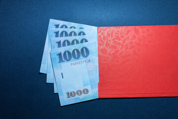 Red envelope and four thousand New Taiwan Dollars (4000 NTD). The concept of giving money, gifts,...
