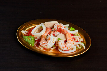 Spicy pork and seafood salad, serve on gold stainless dish
