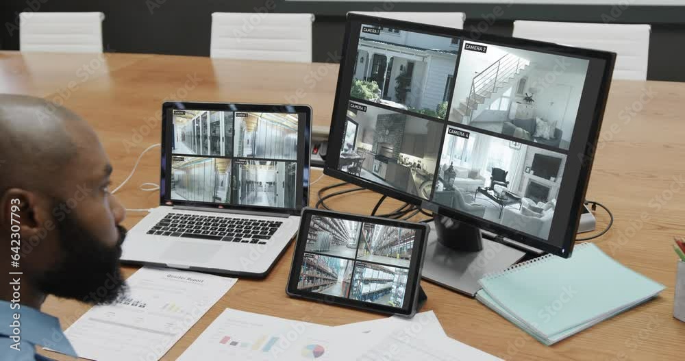 Poster African american male security officer watching cctv camera views on computer screens, slow motion