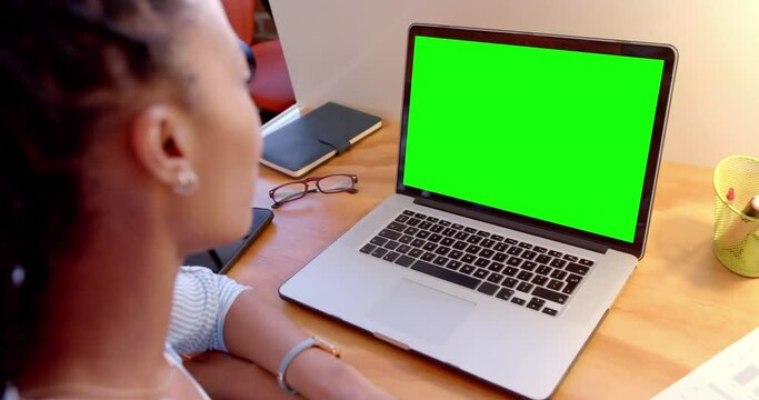 African american casual businesswoman at desk watching laptop with green screen, slow motion