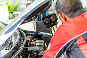 Car mechanic or serviceman refilling air condition and checking a air compressor for fix and repair...