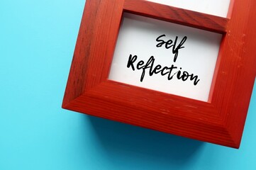 On blue background, photo frame with handwritten SELF REFLECTION, mental process to grow self...